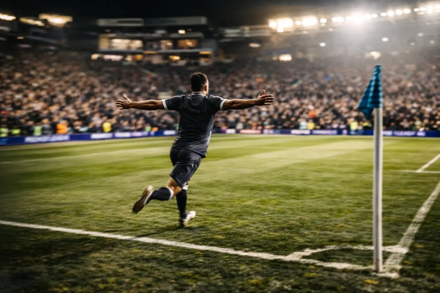 Delantero de fútbol celebrando un gol con los brazos abiertos en el estadio
